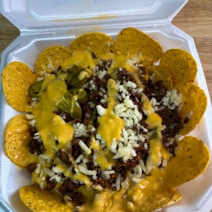 Tortilla chips piled with ground beef, cheese sauce, onion and jalapeños
