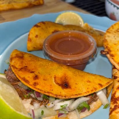 Golden, crispy quesabirria tacos with a cup of consomé and lime