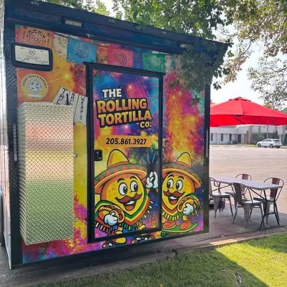 The Rolling Tortilla Co. truck, painted in bright colors with the logo and phone number, next to outdoor tables